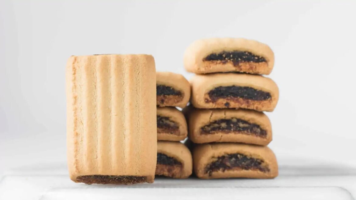Stack of golden-brown jam-filled cookies arranged in a small tower on a white surface
