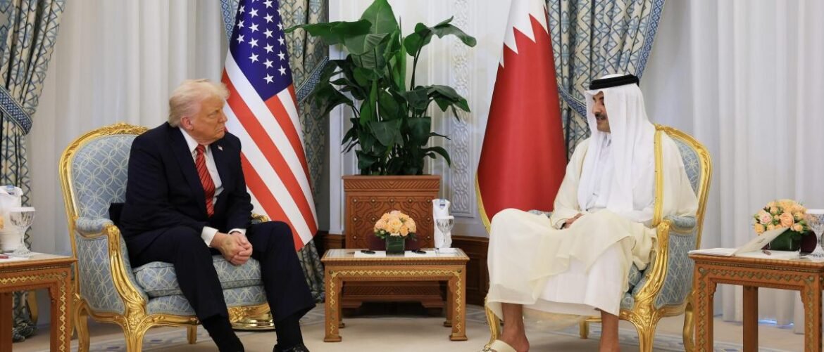 Two men in formal suits sit in ornate gold chairs across from each other in a luxurious room, with the American and Qatari flags in the background.