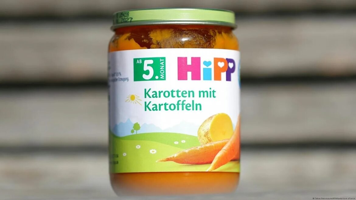 Jar of HiPP carrot-and-potato baby food with a green landscape label on a wooden surface