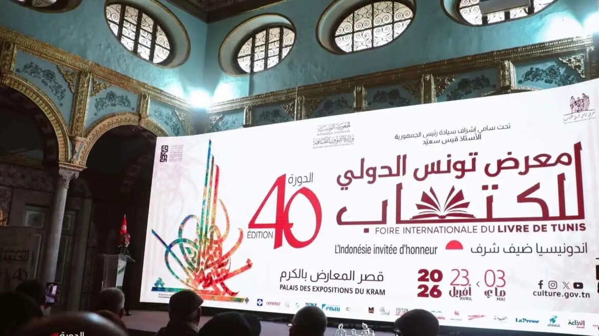 Stage with a large banner for the 40th edition of the Tunis International Book Fair, held at Palais des Expositions du Kram, in a turquoise, ornately decorated hall with arches and circular windows.