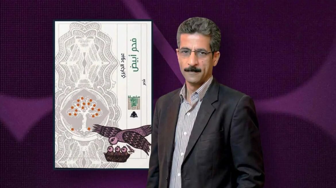 Portrait of a man in a dark suit standing beside a tall ornate book cover with a tree and a bird, against a purple background.