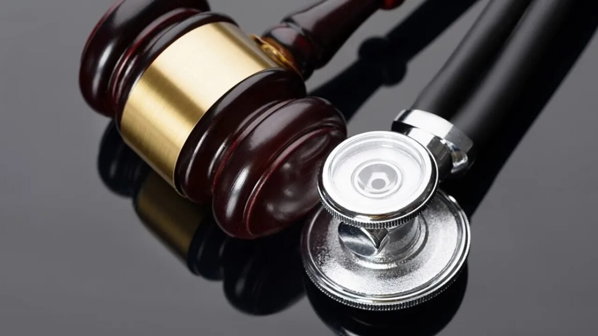 Gavel and stethoscope placed on a reflective surface, symbolizing law and medicine.