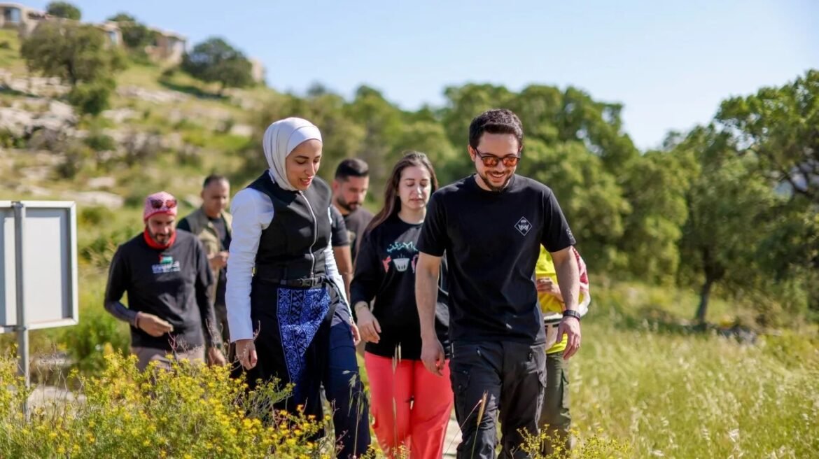 Group of diverse adults walking along a sunny trail through a grassy countryside with trees in the background.