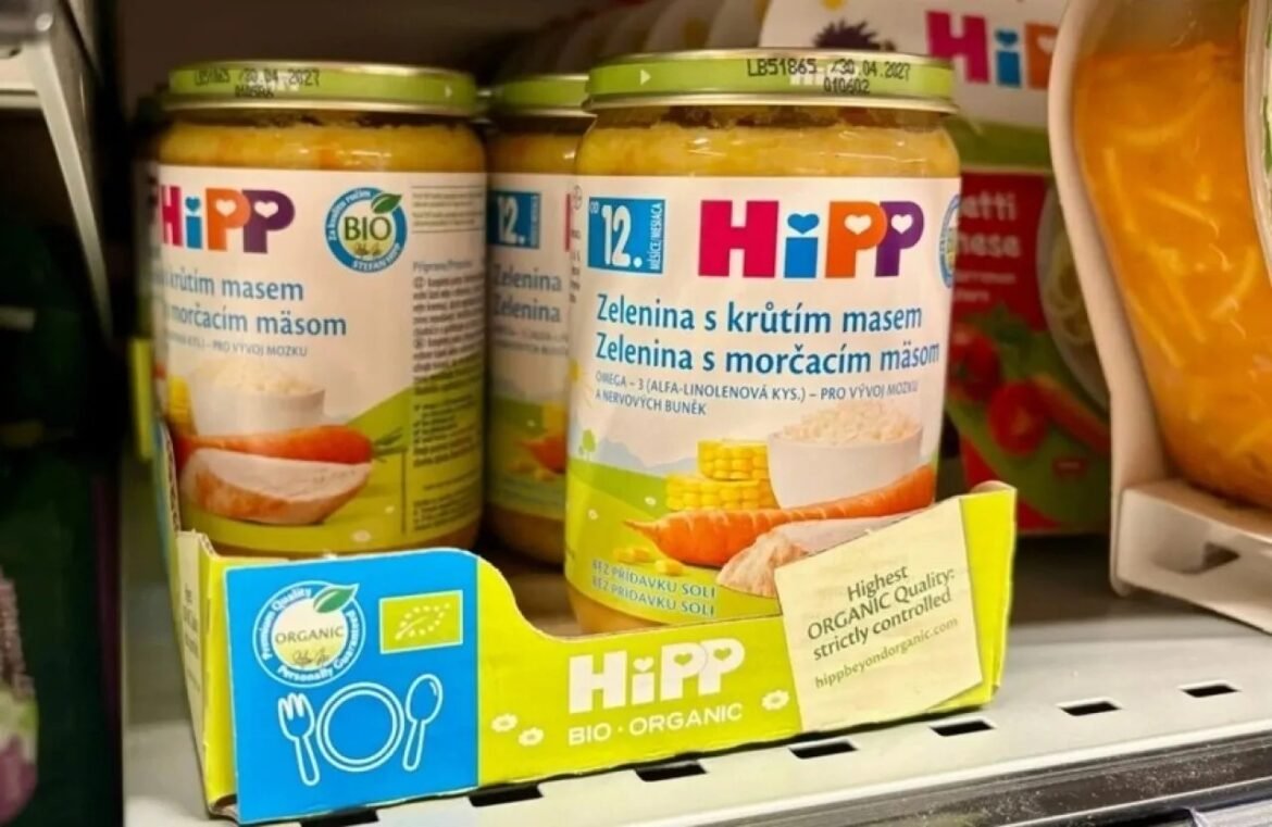 Hipp organic baby food jars on supermarket shelf with carrot and corn imagery (green/yellow labels)