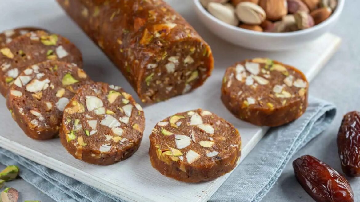 Slices of chocolate nut log with pistachios and almonds on a white cutting board, ready to serve