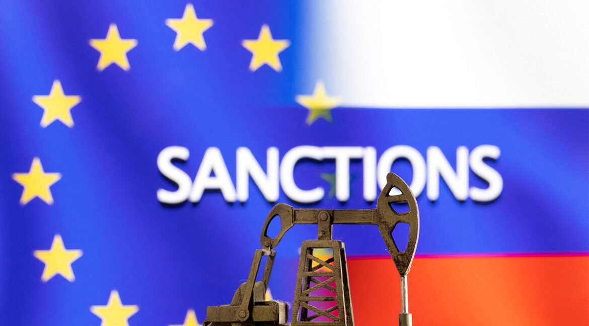 Oil pump jack in the foreground with the European Union flag and the word SANCTIONS in the blurred background.
