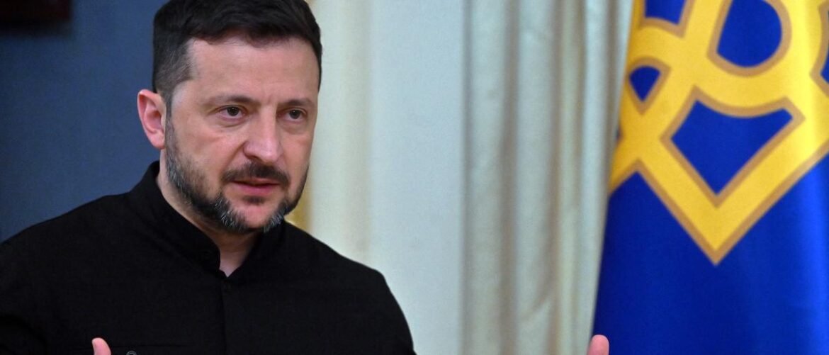 Man in a black shirt speaks, with a blue-and-gold flag in the background.