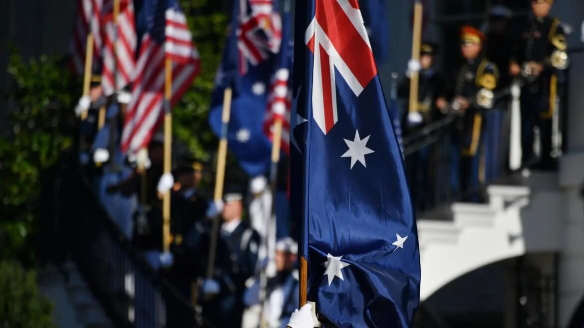 Australian flag in focus at a ceremonial flag-raising with uniformed guards in the background