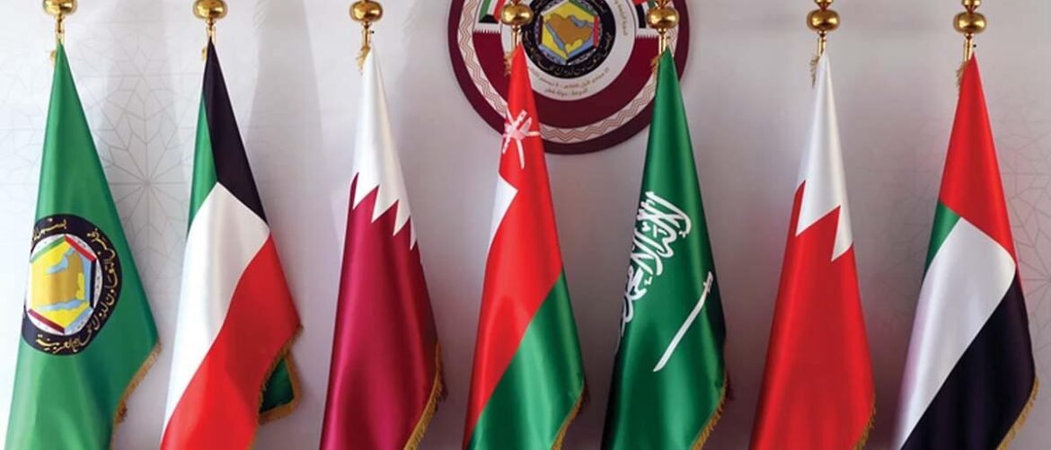 Row of seven ceremonial flags on gold poles in a meeting room, with a circular emblem backdrop behind them.