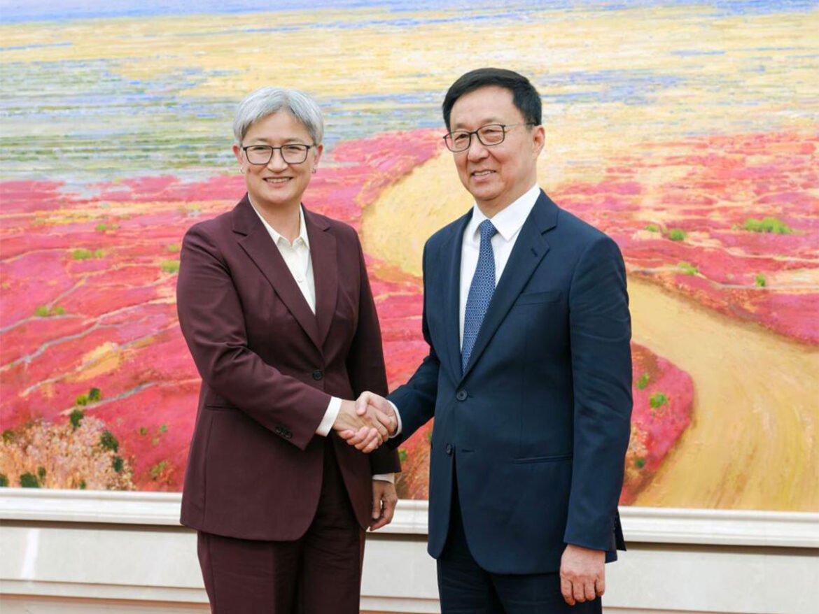 Two professionals in suits shake hands in front of a vibrant landscape painting, signaling a formal meeting or agreement.