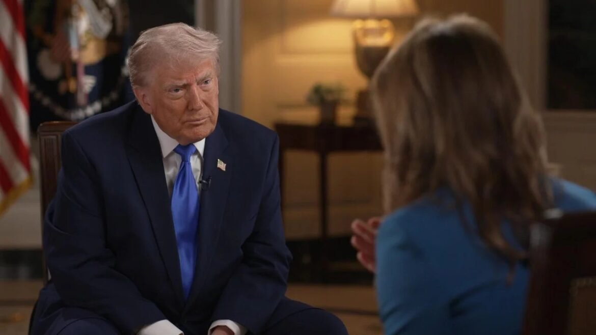 Donald Trump in a navy suit and blue tie being interviewed, facing a woman with her back to the camera in a formal room with an American flag in the background.