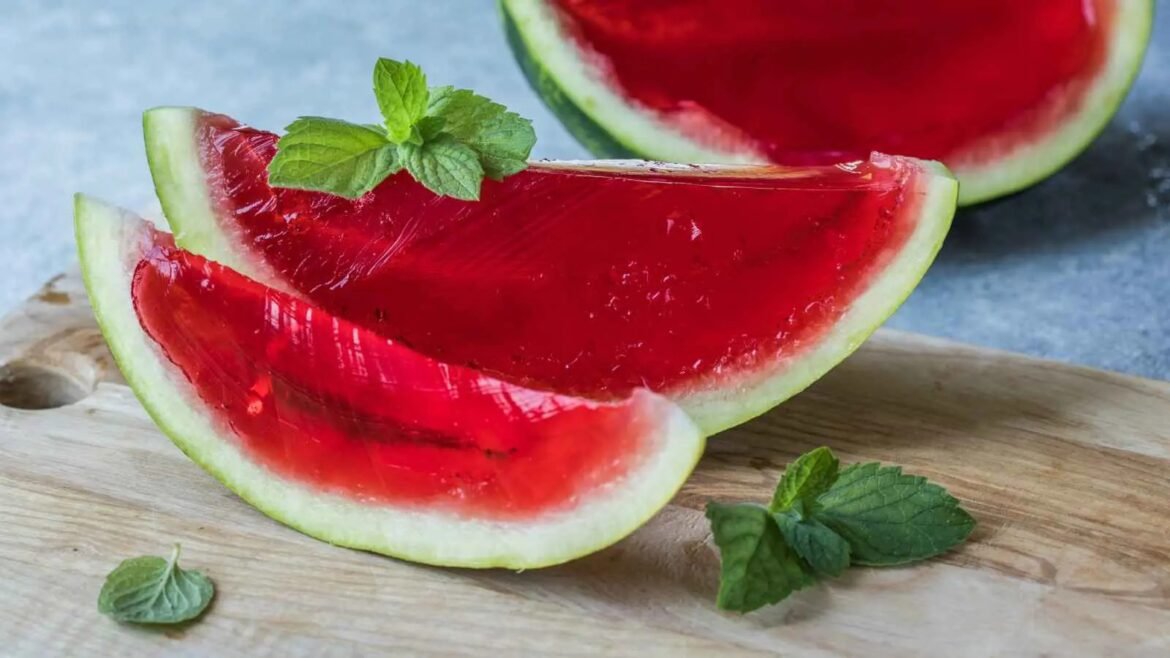 Two bright red watermelon slices on a wooden cutting board, garnished with fresh mint leaves.