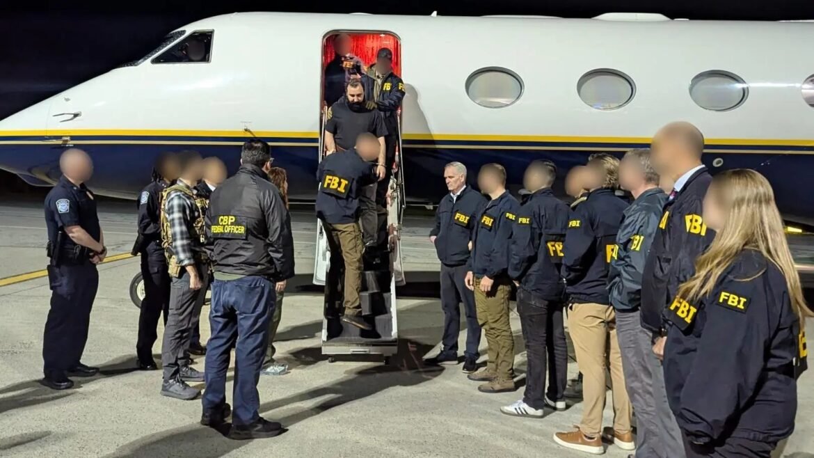 Federal agents (FBI/CBP) escort a detainee down the stairway from a private jet at night, with officers lined up nearby.