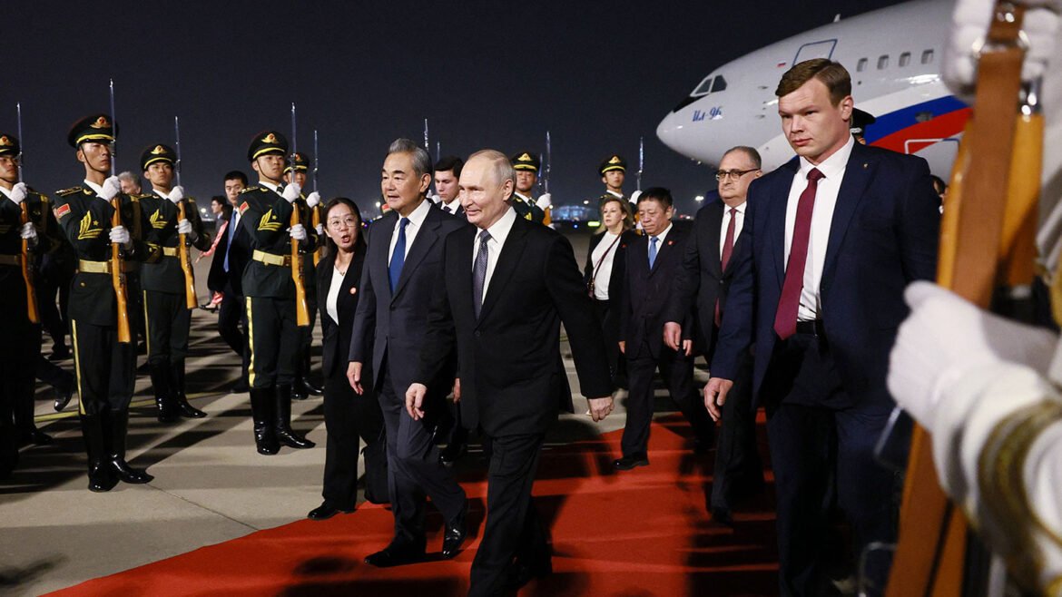 World leaders walk the red carpet during a ceremonial arrival, flanked by uniformed guards at night with a large airplane in the background