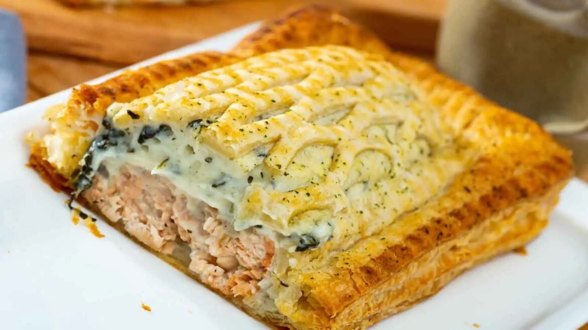 Cross-section of a golden puff pastry loaf filled with creamy tuna and melted cheese.