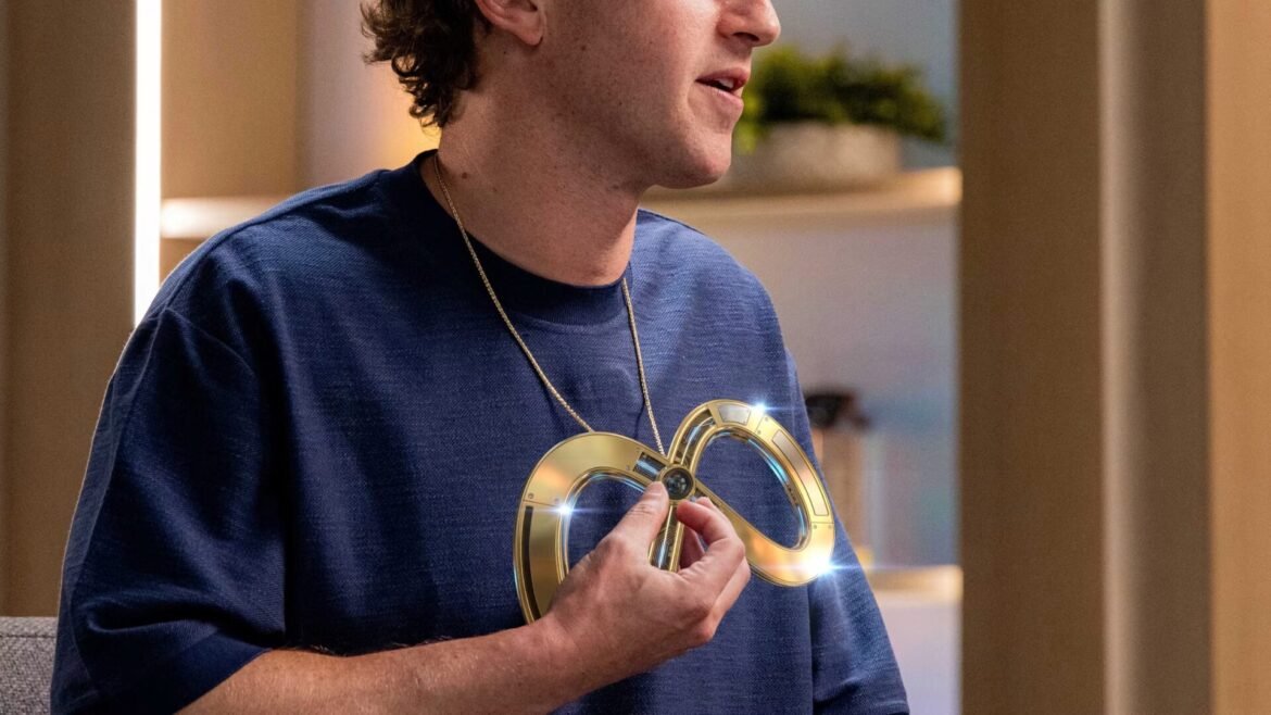Person in a dark blue shirt holds a shiny gold, heart-shaped metal object close to their chest, on a necklace chain visible at the top.