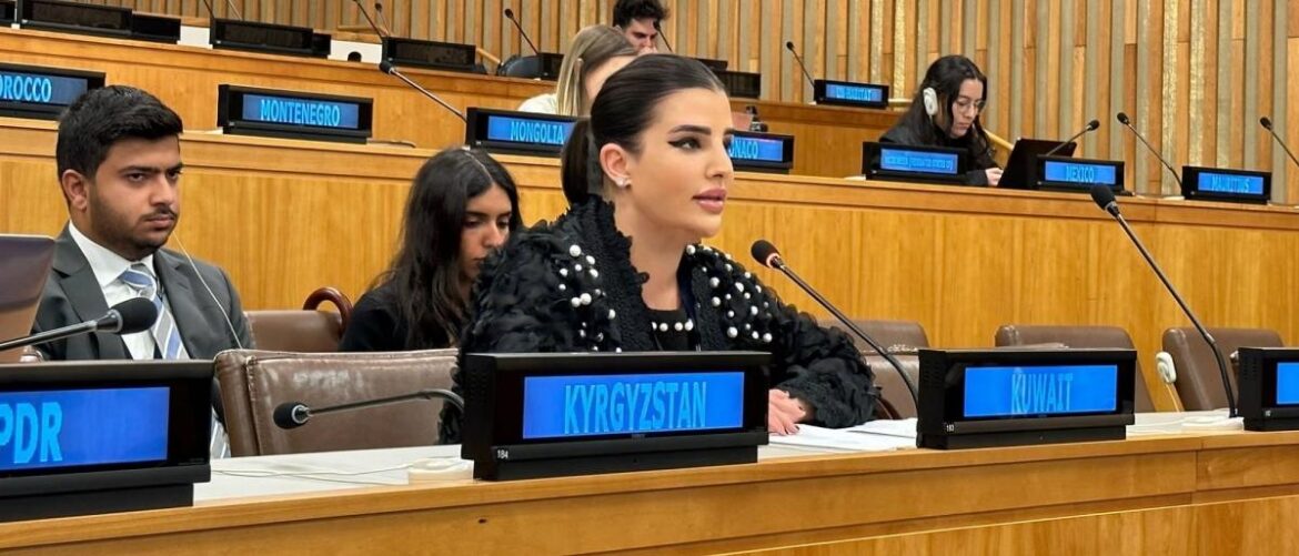 Woman in a studded black outfit speaks into a microphone at a formal conference; Kyrgyzstan nameplate is visible at her desk.