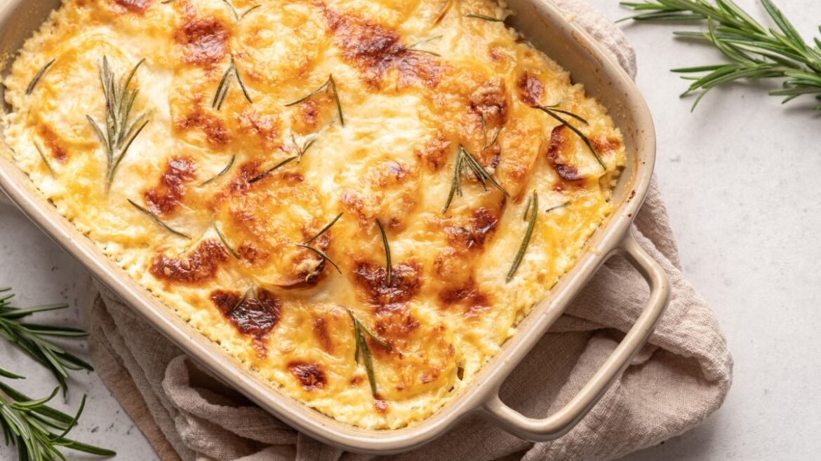 Creamy baked casserole with melted cheese and browned spots, garnished with rosemary.