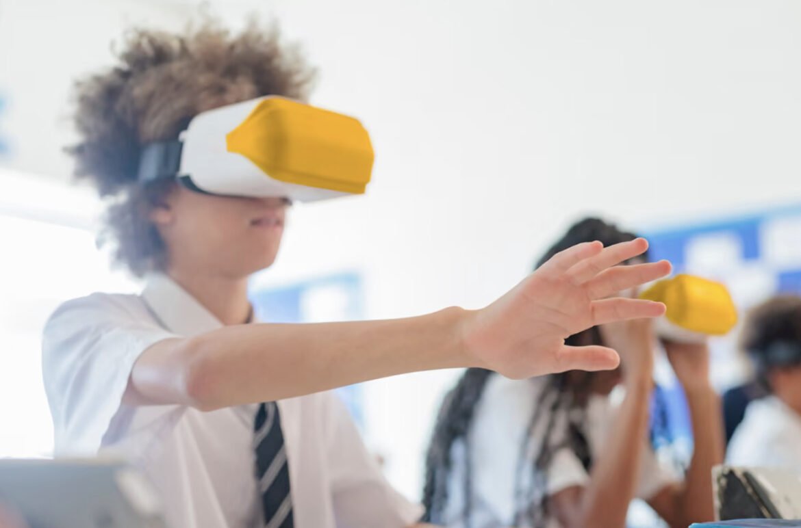 Student in a white shirt and tie wearing a yellow-fronted virtual reality headset, extending a hand forward in a classroom setting.