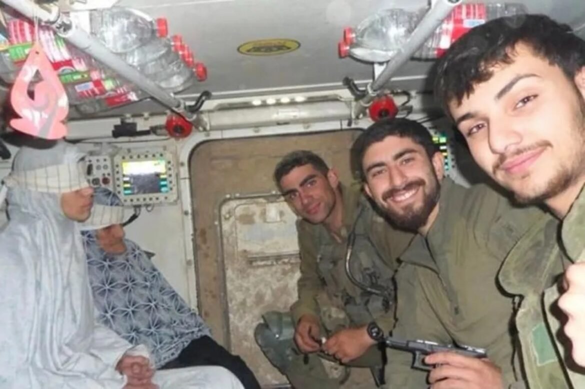 Four men in military uniforms sit inside a small aircraft, smiling at the camera; the man on the left wears a white robe and head covering.