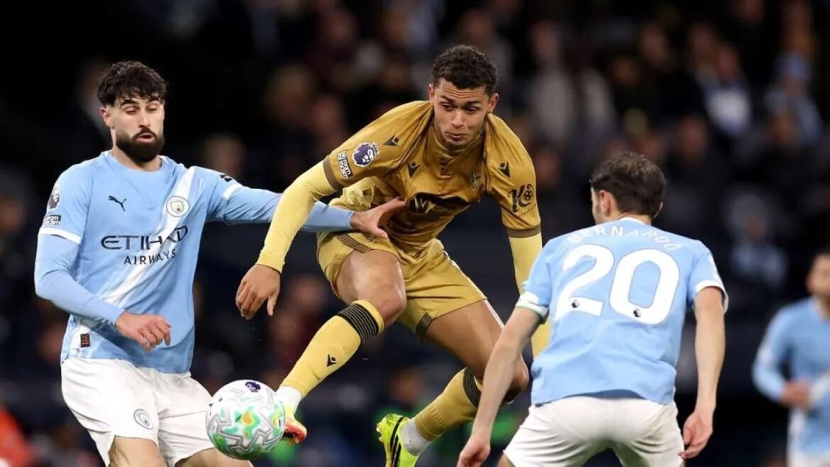 Soccer scene: a gold-kit player leaps to reach the ball while two Manchester City players in light blue challenge him.