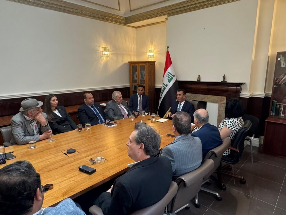 Formal meeting around a large wooden conference table with a flag of Iraq in the background.