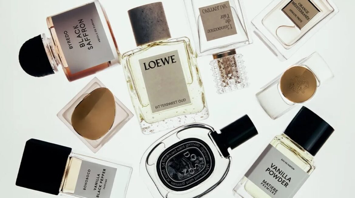 Assorted perfume bottles laid out on a white surface, including a central Loewe fragrance and various others around it.