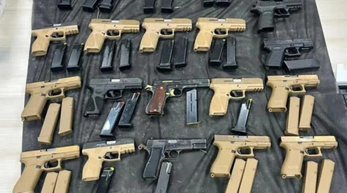 Assortment of semi-automatic pistols and magazines laid out on a black cloth surface.