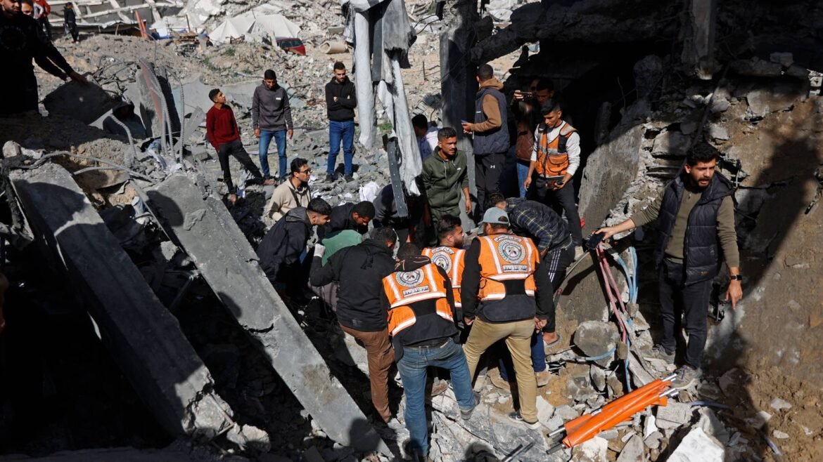 Rescue workers in orange vests and civilians search through rubble at a collapsed building site.