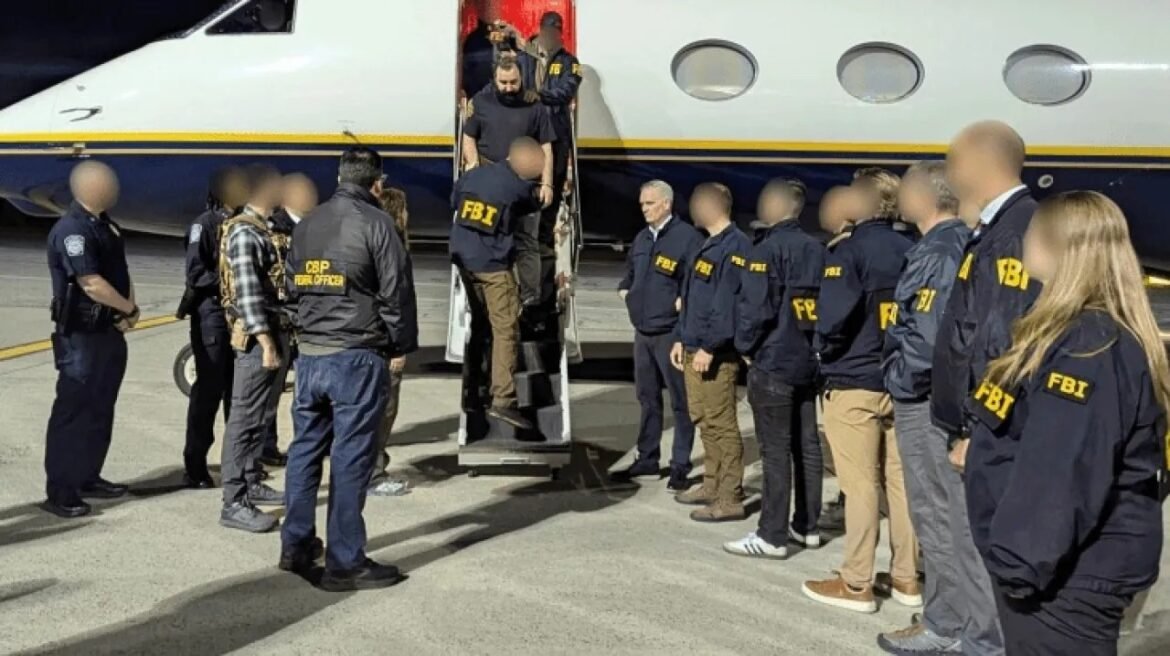 Group of FBI agents in navy jackets guiding individuals up a mobile staircase to a plane on a tarmac at night.