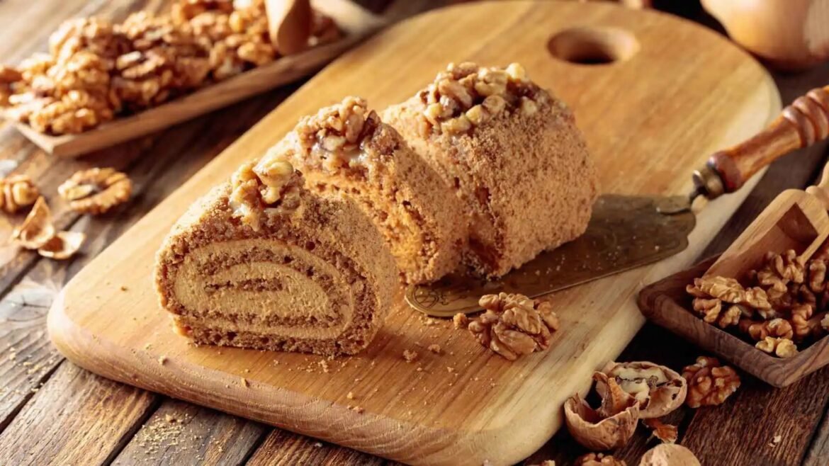 Sliced walnut swirl loaf on a wooden cutting board, topped with chopped walnuts in a rustic kitchen setting.