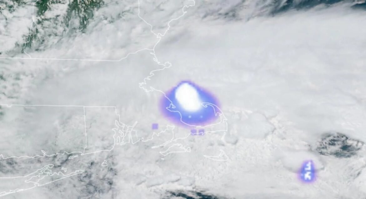 Satellite weather map showing a tropical cyclone near the east coast, white eye with a purple glow and surrounding clouds.