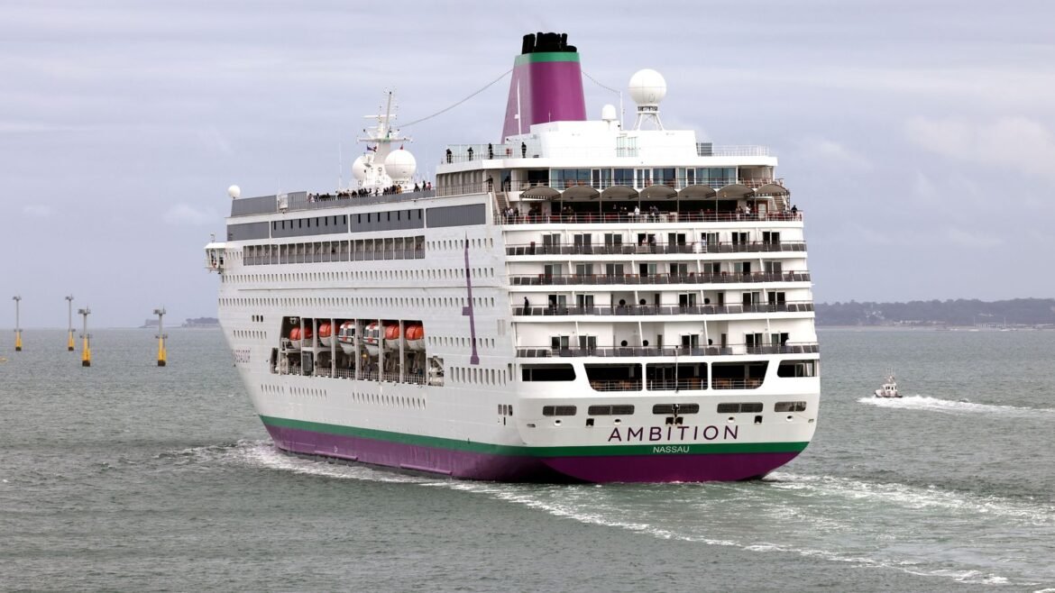Large white cruise ship named AMBITION with purple funnel sails on calm sea, passengers visible on decks.