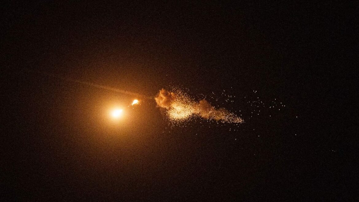 Bright orange rocket or flare with a trailing shower of sparks across a dark night sky, left to right motion.