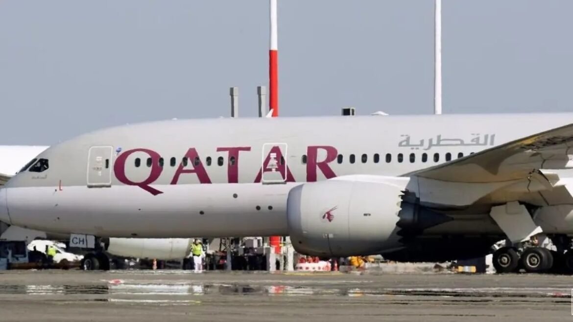 Qatar Airways passenger jet on the tarmac with ground crew working near the nose and engine.