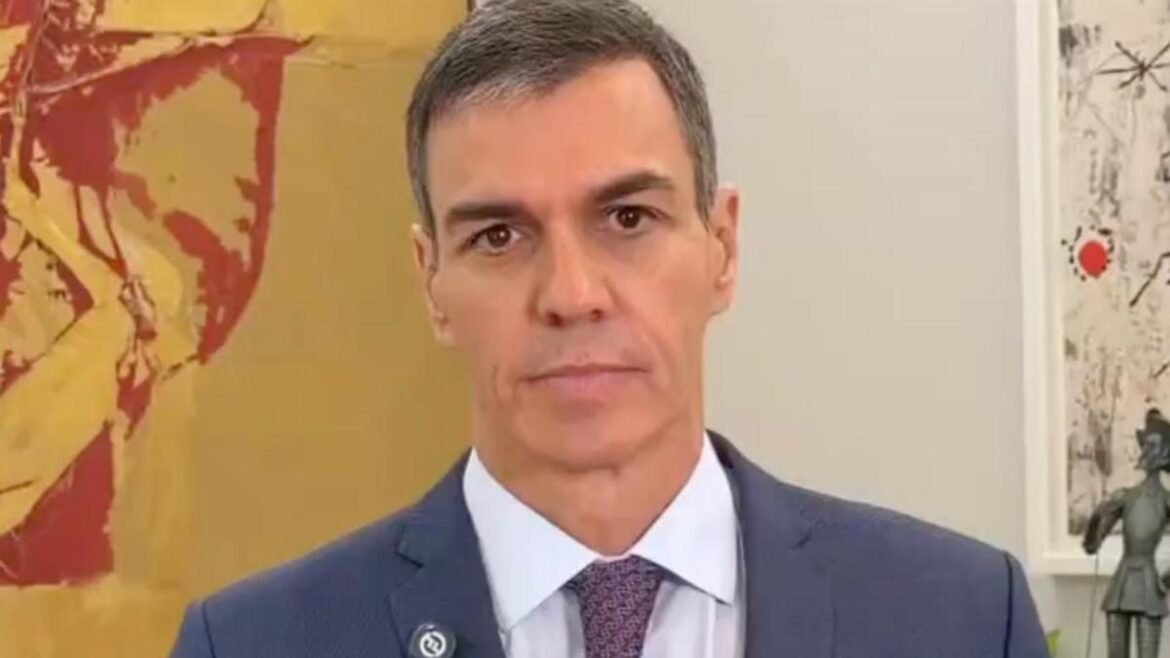 Mid-shot of a man in a navy suit and burgundy tie, looking at the camera, with abstract art behind him.