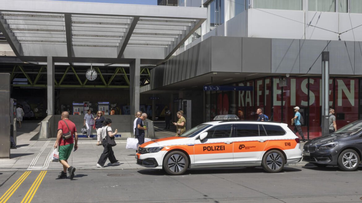 White and orange Polizei station wagon parked outside a modern transit hub with pedestrians nearby.