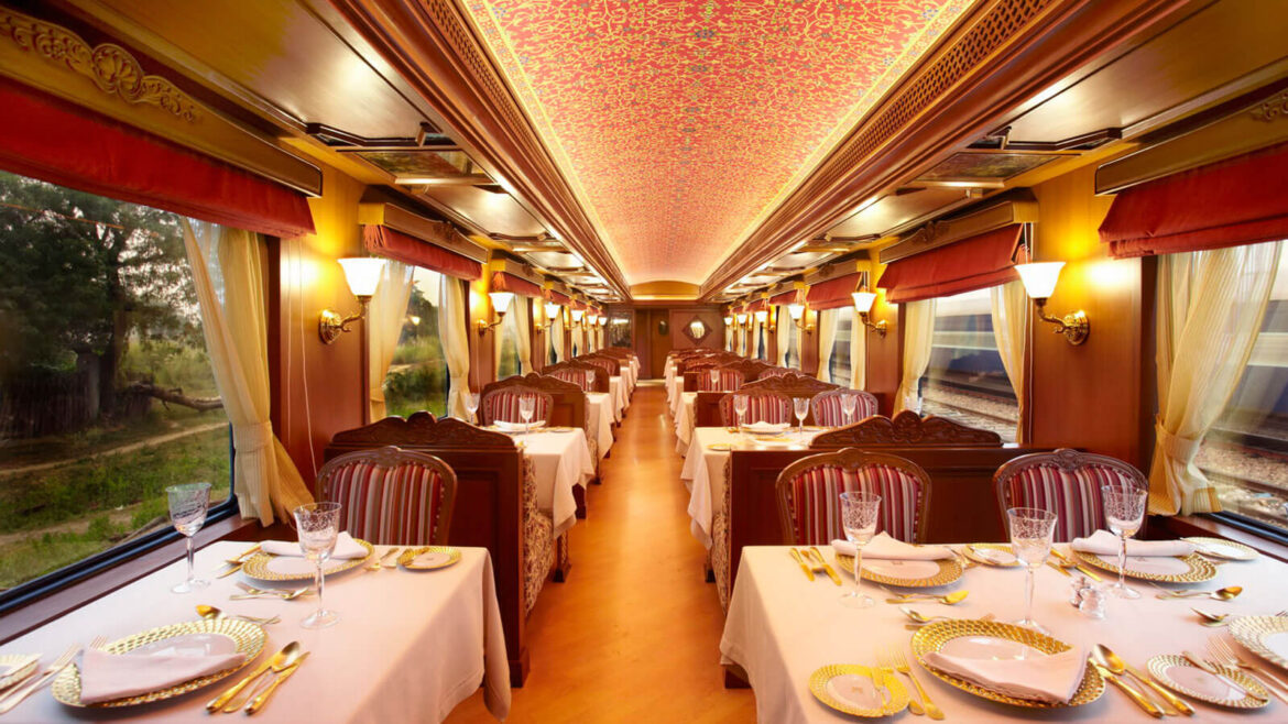Elegant vintage train dining car with tables set for dining along both sides and red striped chairs under warm lighting.