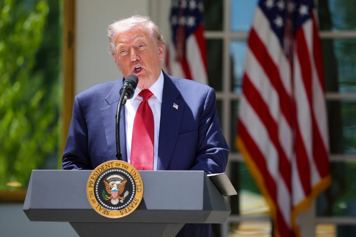 President delivering a speech at a podium with the presidential seal; American flags in the background on an outdoor stage.