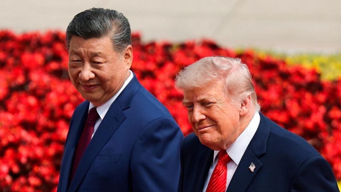 Two men in dark suits walking side by side outdoors, smiling, with a red flower-filled background.
