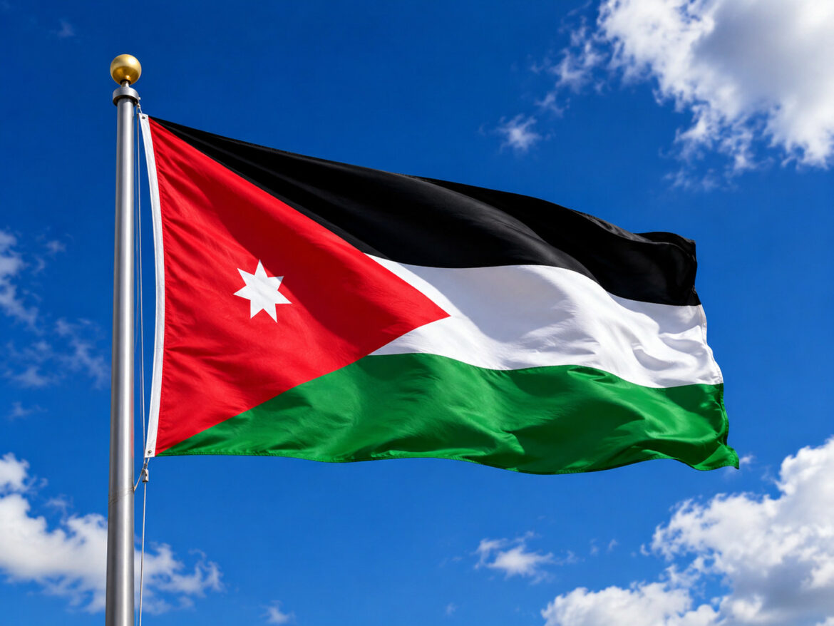 Flag of Jordan waving in the wind against a clear blue sky on a flagpole.