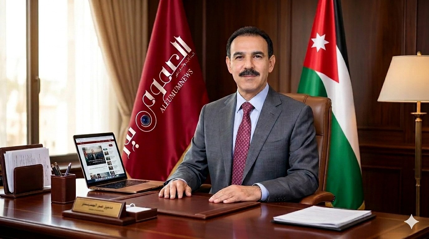 Man in a Gray Suit Sits at a Polished Wooden Desk in an Office with a Jordan Flag Behind Him and a Laptop Open to a News Site  Aleumumnews Aleumumnews | العموم نيوز  Aleumumnews Aleumumnews | العموم نيوز