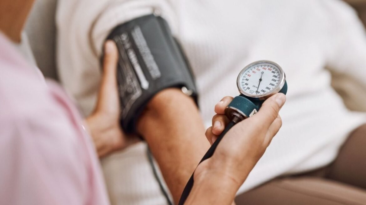Healthcare professional measuring a patient's blood pressure with a cuff and gauge on the arm.