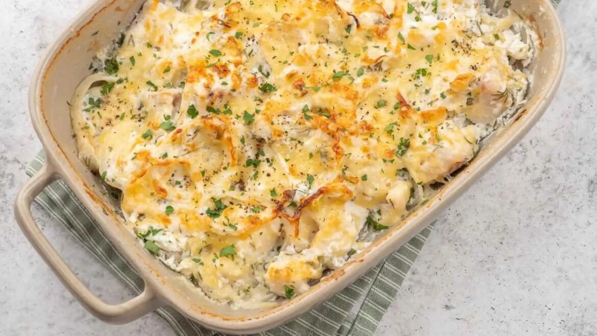 Creamy cheesy potato casserole topped with melted cheese and chopped parsley in a beige baking dish.