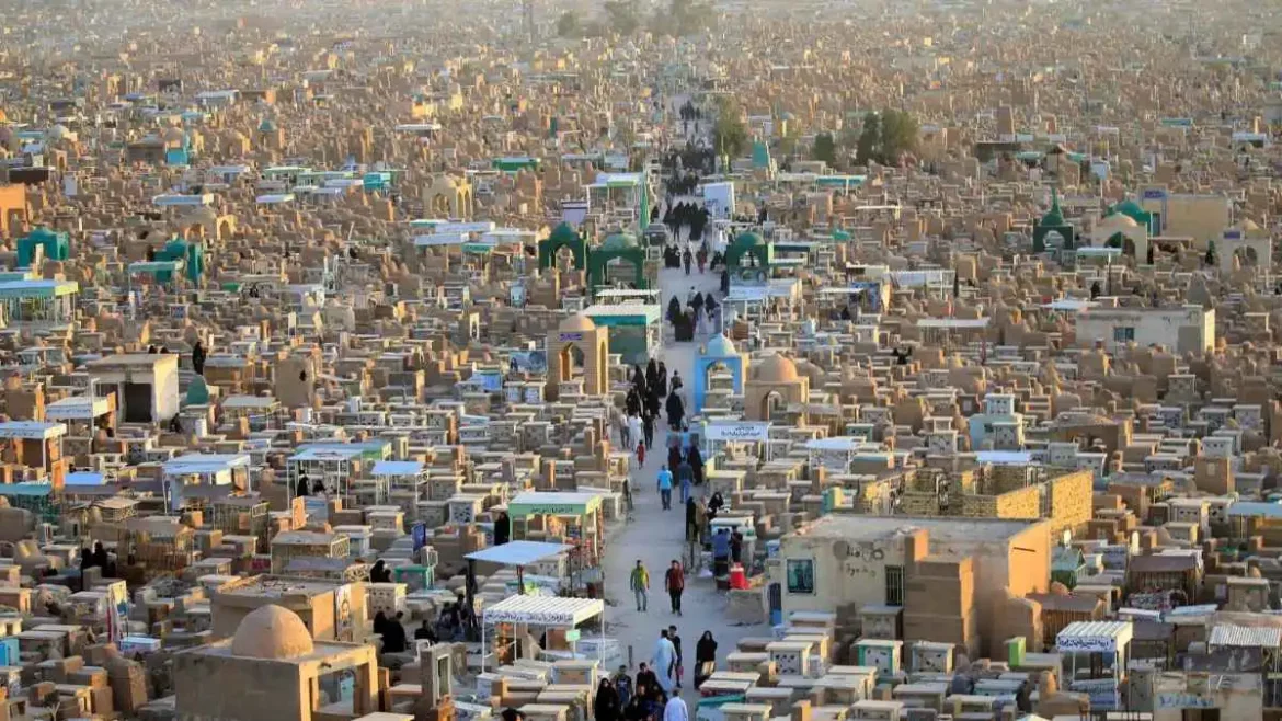 A densely packed desert cemetery with countless tombs and a central path where visitors walk among the graves.