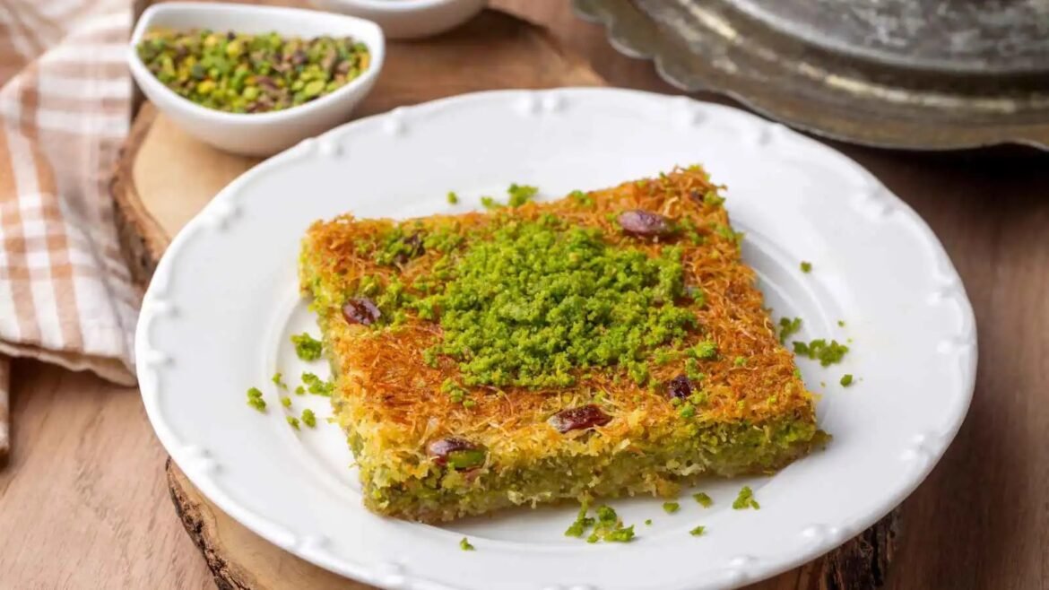 Square kunafa dessert with shredded pastry and bright green pistachio topping on a white plate