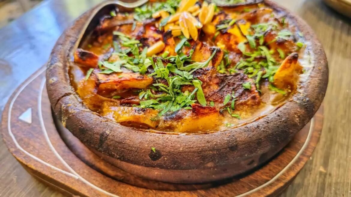 Rustic crusted bread bowl filled with roasted potatoes, melted cheese, and fresh chopped herbs on a wooden board