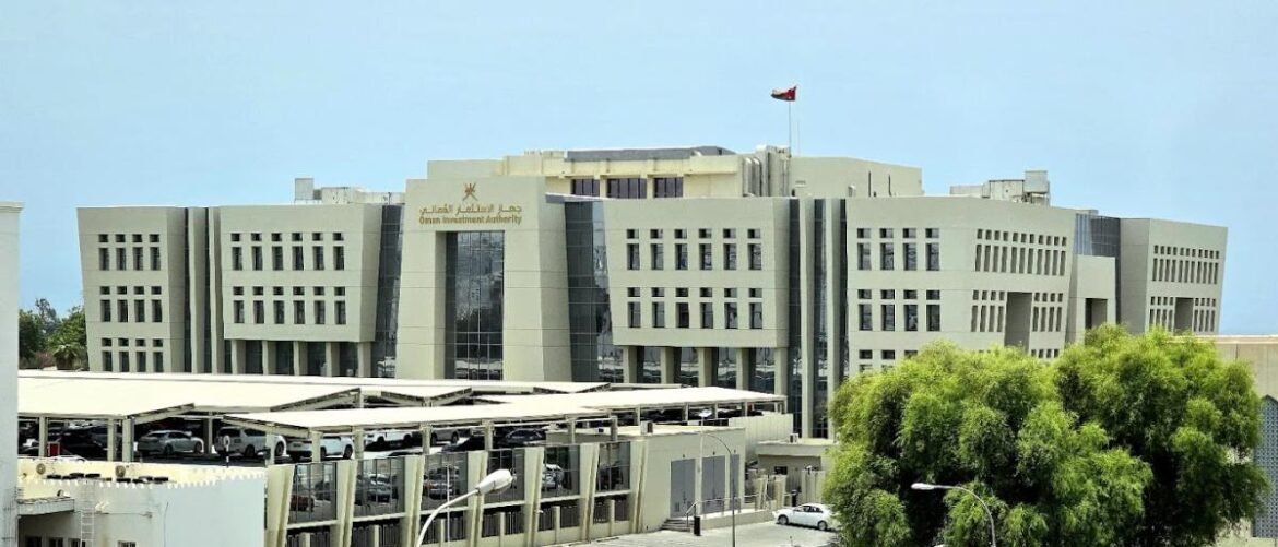 Front view of the Oman Investment Authority building, a large modern office complex with a flag on top and surrounding parking areas.