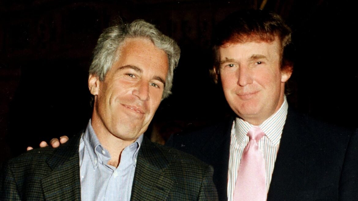 Two men in jackets smiling for a photo, one with gray hair on the left and the other with darker hair on the right.