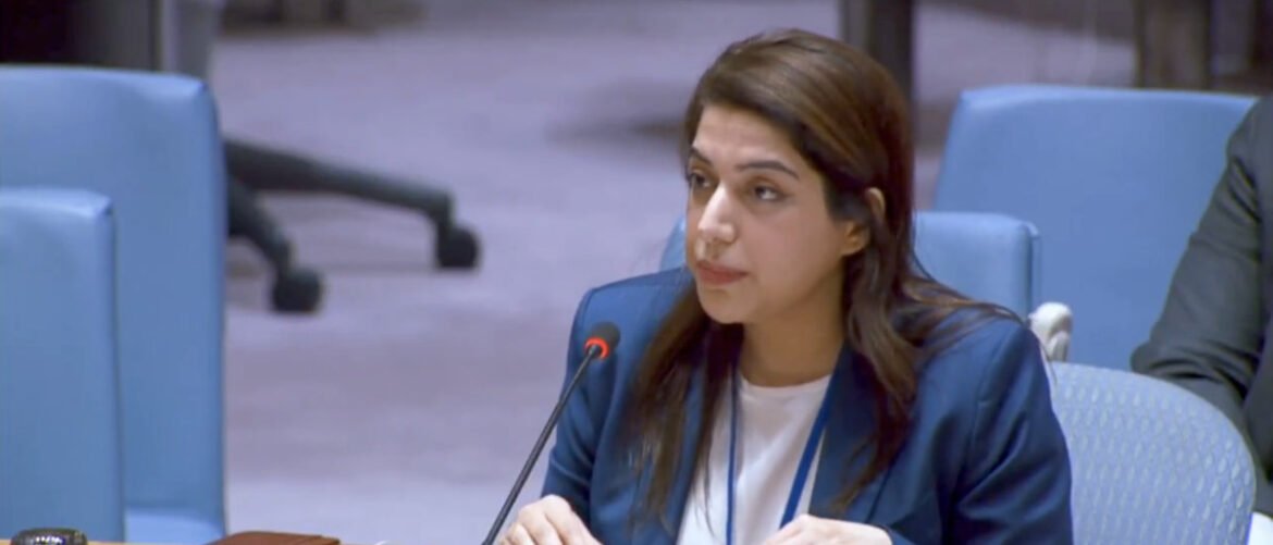 Woman in a blue blazer speaks into a microphone at a conference panel statement slot.